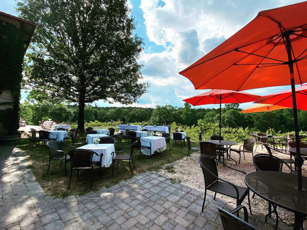 A patio with tables, chairs and umbrellas 