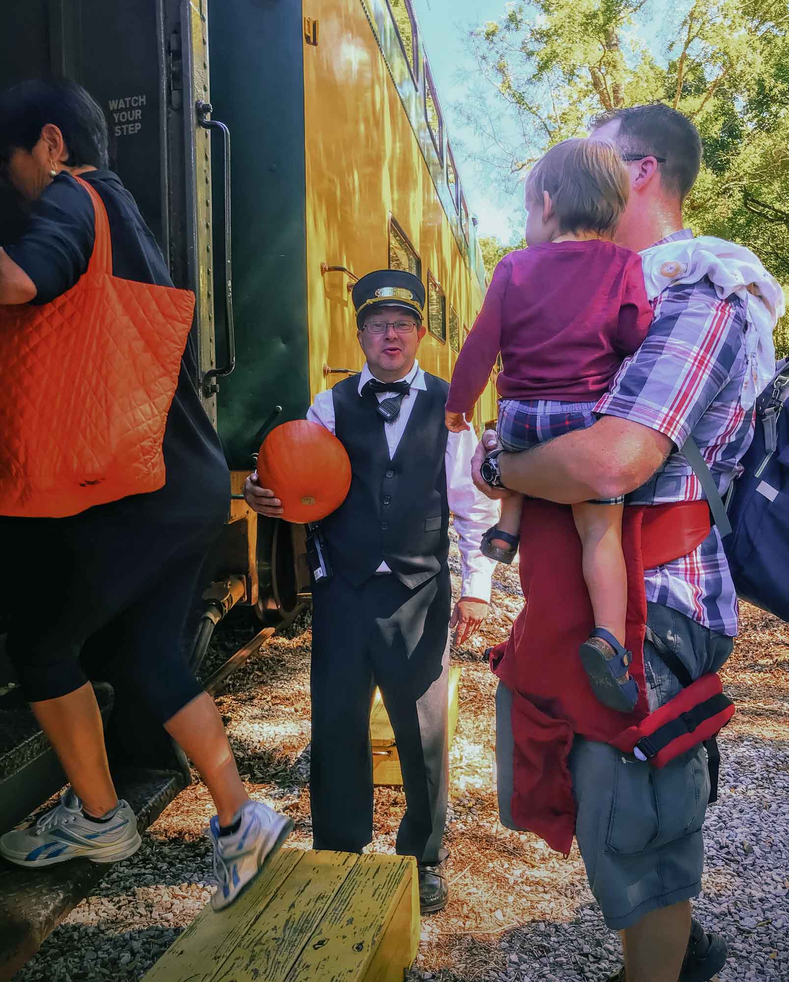 Conductor holding a pumpkin while helping passenge